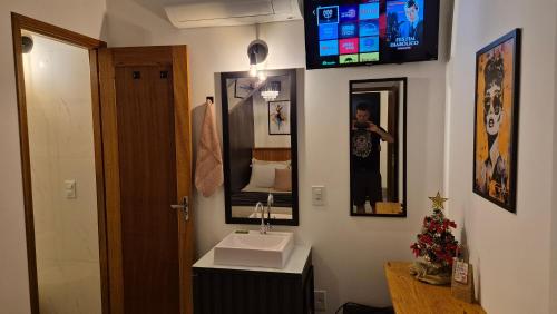 a bathroom with a sink and a tv on the wall at Stúdio 7 climatizado, centro-terreo-privativo in Domingos Martins