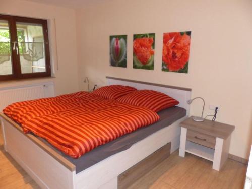 ein Bett mit einer orangefarbenen Bettdecke in einem Schlafzimmer in der Unterkunft Ferienwohnung Paula in Sankt Johann
