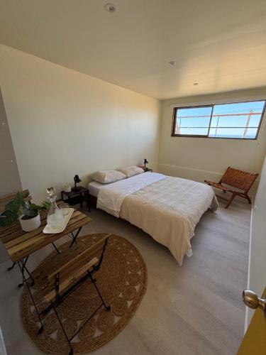a bedroom with a bed and a table and a window at Hostal ídem in Valparaíso