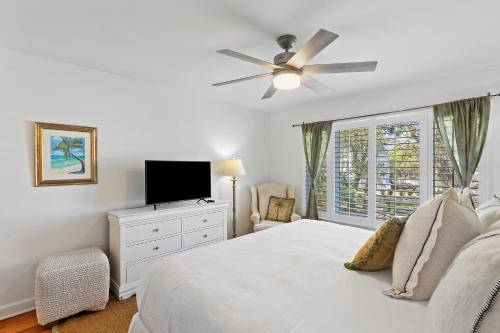 a white bedroom with a bed and a television at SG7A: 7A Seagrove Villa in Isle of Palms