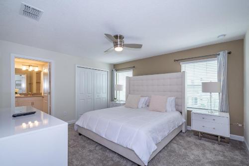 a bedroom with a white bed and a ceiling fan at 4809AM TOWNHOUSE 4 BEDROOMS & 3 BATHROOMS + POOL in Kissimmee