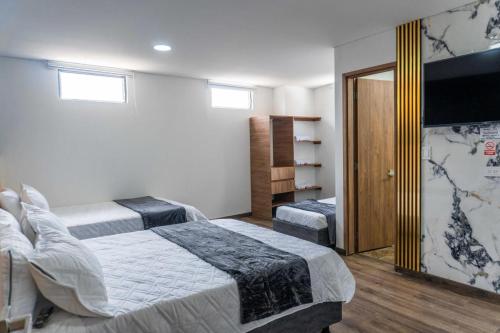 a bedroom with two beds and a flat screen tv at Hotel Salinero - Zipaquirá in Zipaquirá