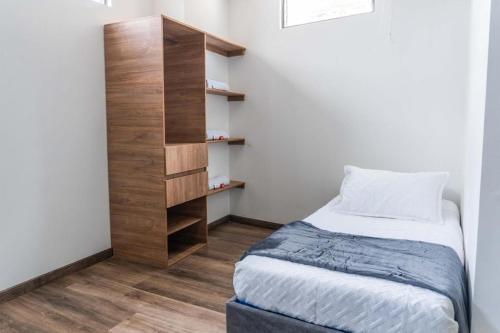 a small bedroom with a bed and a book shelf at Hotel Salinero - Zipaquirá in Zipaquirá
