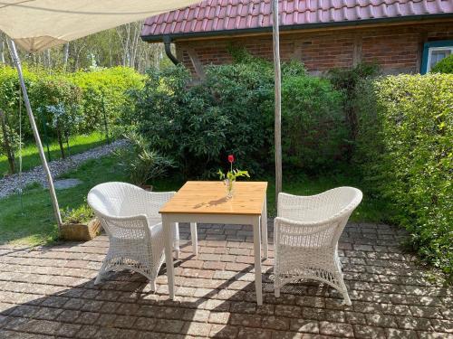 a table with three chairs and an umbrella at Großzügiges Studio In Einem Kleinen Fachwerkhaus in Dömitz