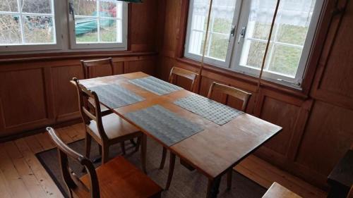 a wooden table and chairs in a room with windows at Ferien In Der Vogelherd in Wolfhalden 