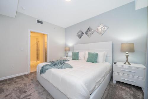 キシミーにある3151-307BE STOREY LAKE, CONDO 2/2 LAKE VIEWの白いベッドルーム(緑の枕が付いた大きな白いベッド付)