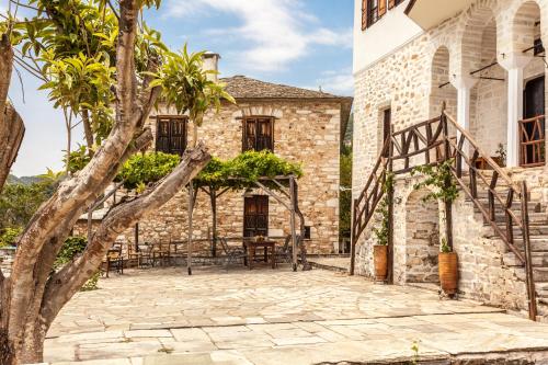 an outdoor patio of a stone house with a tree at Archontiko Filippidi in Miléai