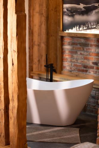 a white bath tub in a room with a brick wall at Pension U Studny in Harrachov