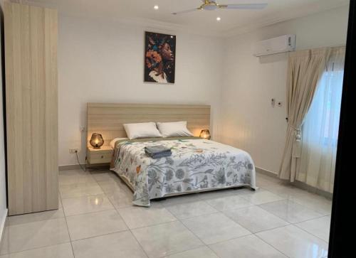 a bedroom with a large bed with two lamps on it at Legacy Square Apartment in Accra
