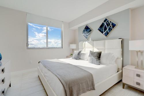 a white bedroom with a large bed and a window at 3900-902CH DESIGN DISTRICT, CONDO 2 BEDROOMS & 2 BATHROOMS in Miami