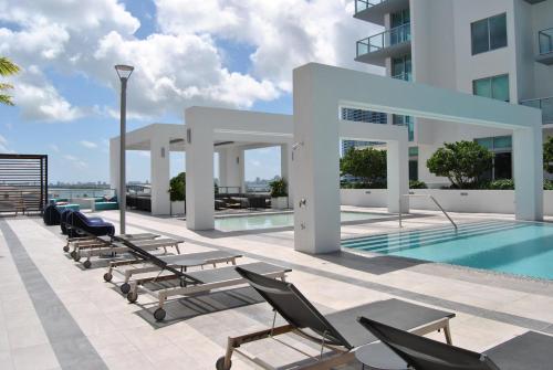 a swimming pool with chaise lounge chairs next to a building at 3900-902CH DESIGN DISTRICT, CONDO 2 BEDROOMS & 2 BATHROOMS in Miami