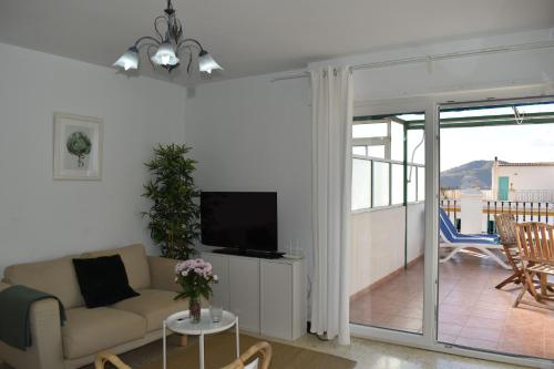 a living room with a couch and a tv and a balcony at Zentral Gelegene Wohnung in Cómpeta