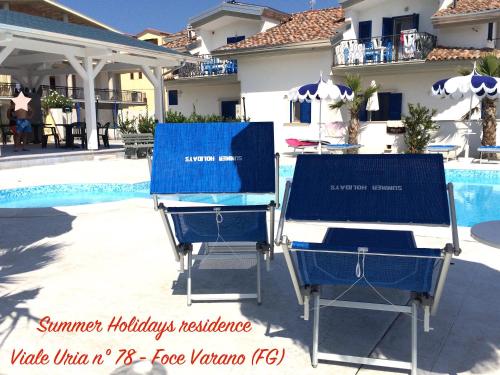 two beach chairs sitting next to a swimming pool at Summer Holidays Apartments in Foce Varano
