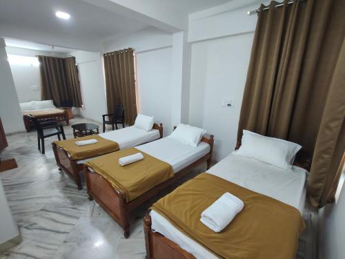 a hotel room with two beds and a desk at SHREVIK Comforts in Chikmagalūr