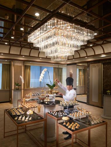 a chef preparing food in a large room with a chandelier at Amari Don Muang Airport Bangkok in Bangkok