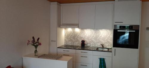 a kitchen with white cabinets and a white refrigerator at Rothorn Center A 1Og Schöpfer in Sörenberg