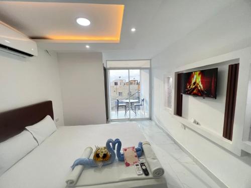 曼塔Hostal Las Orquideas 2的一间白色房间，里面有一张床、一台电视和一张床 sidx sidx