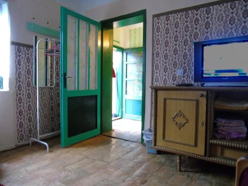 Una sala de estar con una puerta verde y un televisor. en STD Kod Makse, kuca na jezeru Kraljevac, en Deliblato