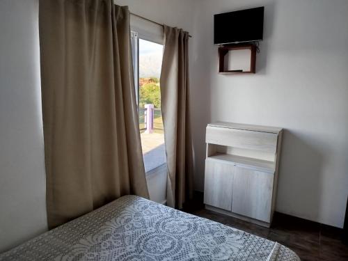 een slaapkamer met een bed en een raam met een televisie bij Flor silvestre in Carpintería