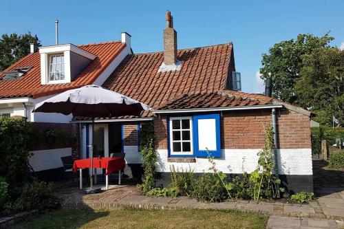 a house with a red roof and a table and an umbrella at Charming house in Westenschouwen in Burgh Haamstede
