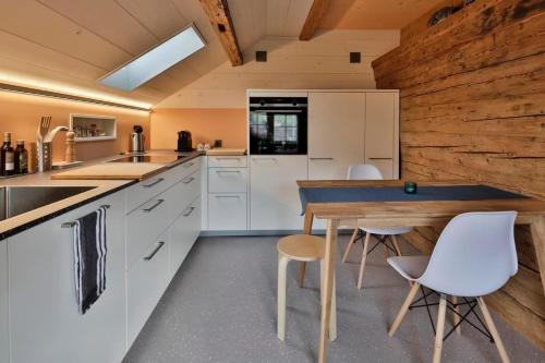 KrummenauにあるHaus Zum Rehの白いキャビネットとテーブルと椅子のあるキッチン