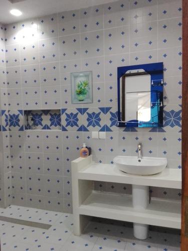 a bathroom with blue and white tiled walls and a sink at keur Baye fall fall saly in Sali Nianiaral