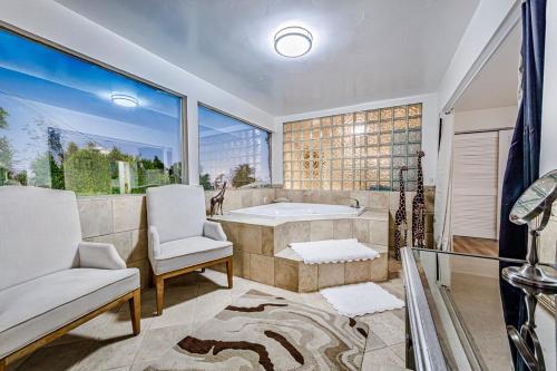 un bagno con vasca, sedia e finestra di The Palm Diamond a Luxury Poolside and Golf Oasis a Palm Springs
