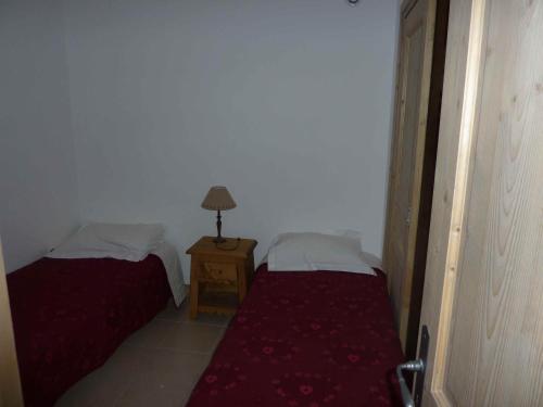 een kamer met twee bedden en een lamp op een tafel bij Le Hameau des Neiges in Demi-Quartier