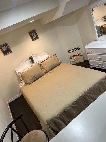 a large bed in a room with a dresser at bachelor basement apartment with private kitchenette, washroom, and parking in Toronto