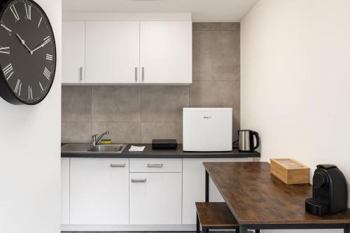 a kitchen with white cabinets and a clock on the wall at Apartments KR in Cologne