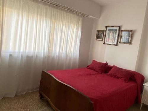 - une chambre avec un lit doté de draps rouges et une fenêtre dans l'établissement Departamento frente al mar, à Necochea
