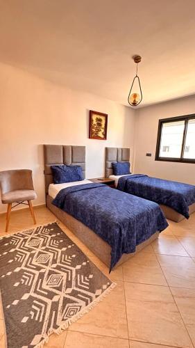 a bedroom with two beds with blue sheets and a rug at Appartement de luxe à khouribga in Khouribga