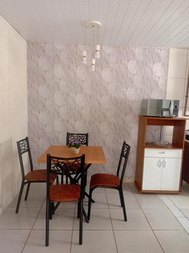 ein Esszimmer mit einem Tisch und vier Stühlen in der Unterkunft Casa térreo in São José dos Pinhais