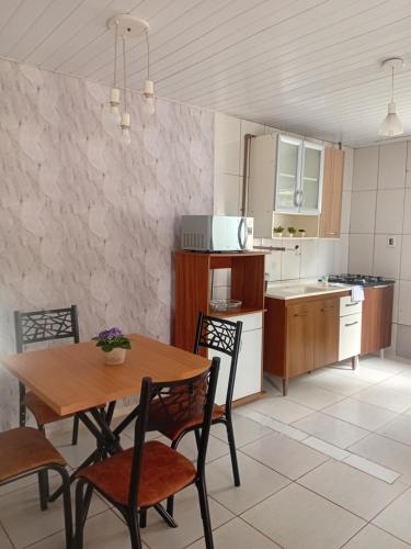 eine Küche mit einem Holztisch und Stühlen in der Unterkunft Casa térreo in São José dos Pinhais