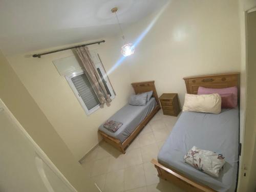 Dos camas en una habitación pequeña con ventana. en Gzenaya, en Tánger