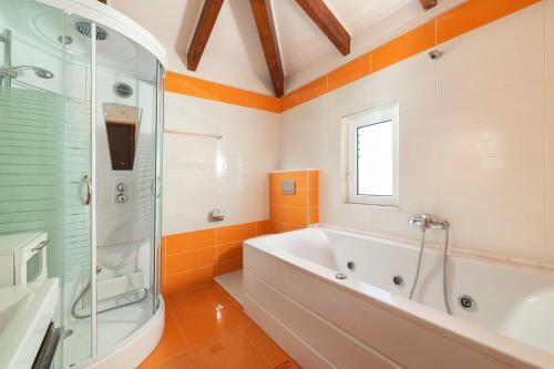een oranje en witte badkamer met een bad en een douche bij Haus In Kolympia Mit Garten Und Bergblick in Kolimbia