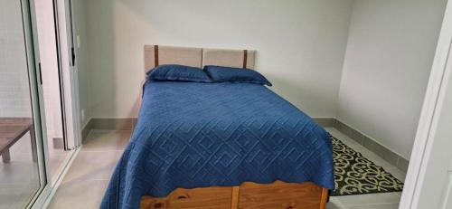 - un lit avec une couette bleue dans l'établissement Apartamento Novo em São Lourenço, à Bertioga