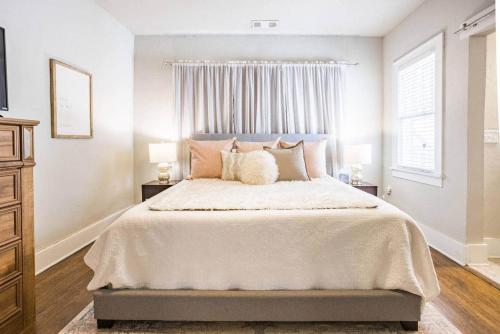 une chambre blanche avec un grand lit avec des oreillers dans l'établissement Owen Bungalow II - OKC Paseo - HOT TUB & Fire Pit, à Oklahoma City