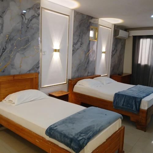 a hotel room with two beds and two lamps at Residence Annapurna Indian in Dakar