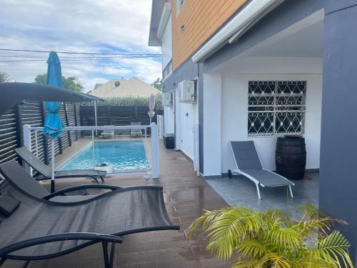une terrasse avec une piscine et des chaises ainsi qu'une maison dans l'établissement L'améthyste, à Saint-François
