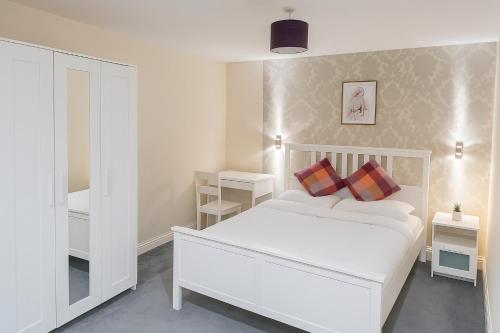 une chambre blanche avec un lit blanc avec deux oreillers dans l'établissement Spacious Modern 5 bedroom home near Heathrow Windsor, à Canvey