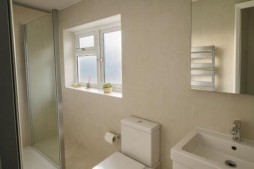 une salle de bain avec toilettes, lavabo et fenêtre dans l'établissement Spacious Modern 5 bedroom home near Heathrow Windsor, à Canvey