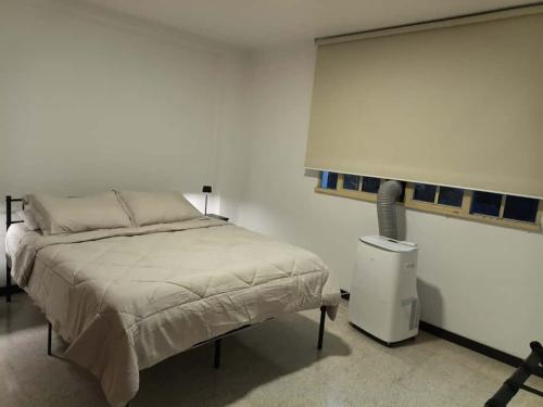 a white bedroom with a bed and a window at Aoartamento Remodelado Zona Cèntrica de Caracas in Caracas