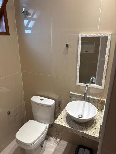 a bathroom with a white toilet and a sink at Quintal da Espera - Praia de Itacimirim in Camacari