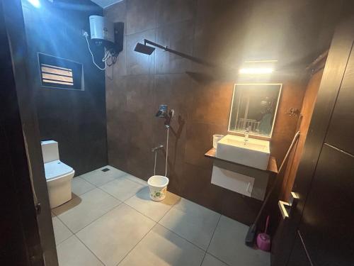 ein Badezimmer mit Toilette, Waschbecken und Spiegel in der Unterkunft Grand Sapphire Resorts & Travels Idukki in Idukki