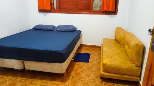 ein Bett und ein Stuhl in einem Zimmer in der Unterkunft Chacara vida nova em Pedro de toledo in Pedro de Toledo