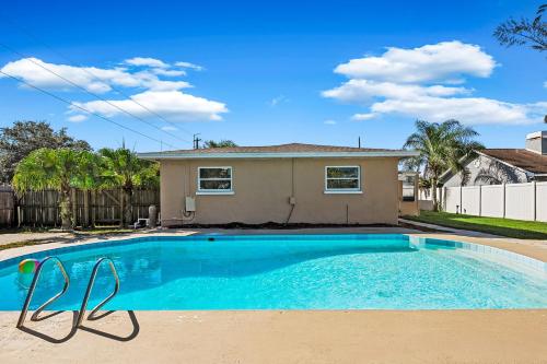 a pool with two chairs in front of a house at Private 5BR Oasis with Pool Near Clearwater Beach in Clearwater