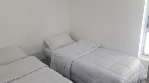 a white bedroom with two beds and a window at Double Kit 404 - 2 Quartos Perto UNB in Brasilia