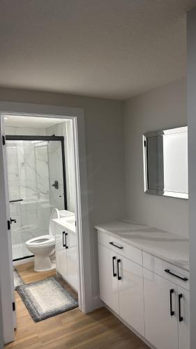 ein weißes Badezimmer mit Toilette und Waschbecken in der Unterkunft Airlux in Nisku