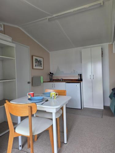 a kitchen with a table and two chairs and a white table at Captains Quarters in Ohope Beach